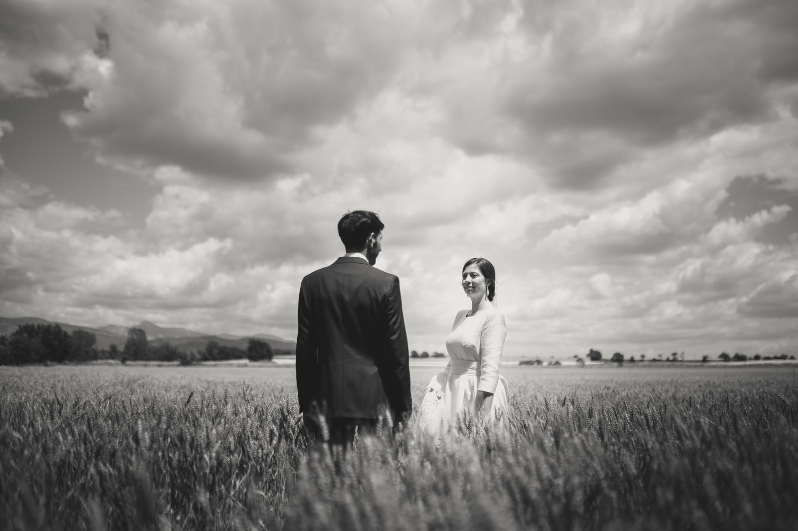 Novios en un campo de cereal bajo un cielo de nubes