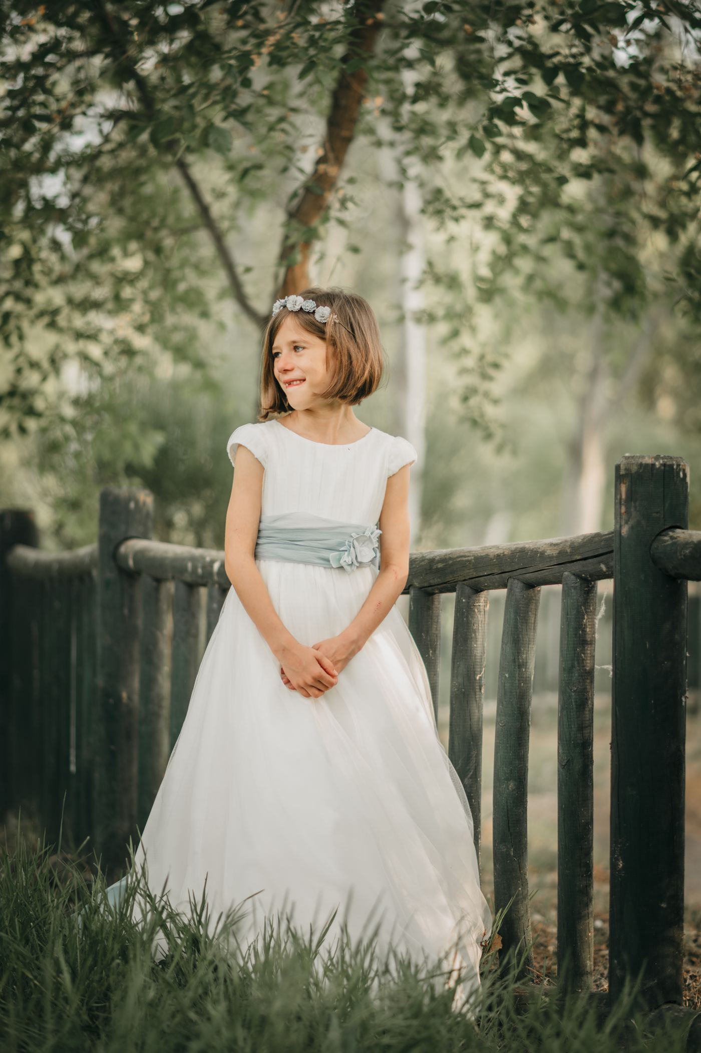 Niña de comunión apoyada en una valla de madera