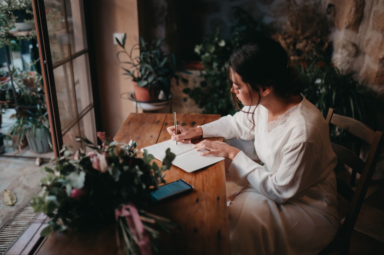 Novia escribiendo una carta junto a una ventana antes de la boda