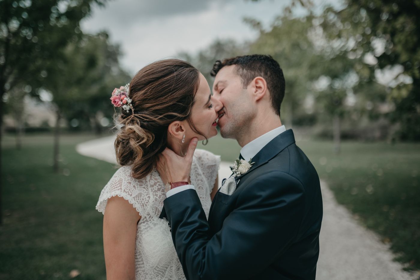 Novios besándose en un paseo arbolado el día de su boda